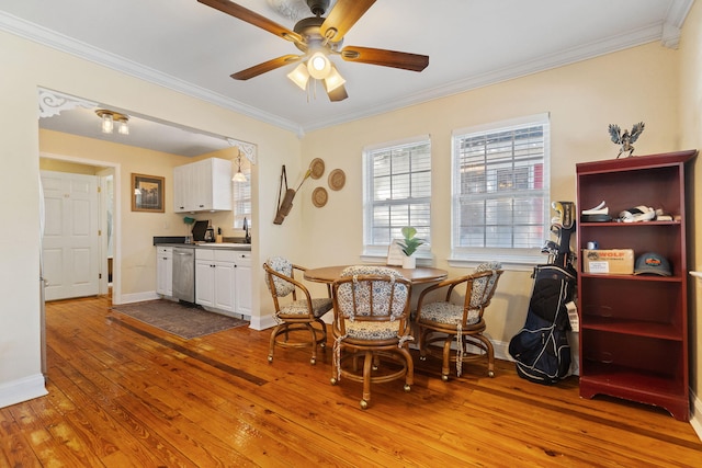 dining room featuring a ceiling fan, crown molding, baseboards, and wood finished floors