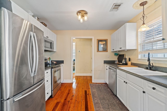 kitchen with dark countertops, visible vents, appliances with stainless steel finishes, and white cabinets