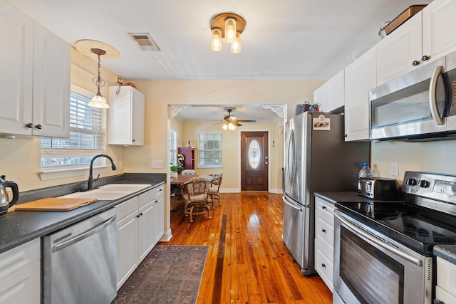 kitchen featuring decorative light fixtures, dark countertops, visible vents, appliances with stainless steel finishes, and white cabinets