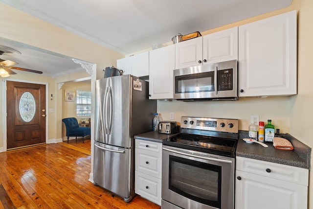 kitchen with stainless steel appliances, dark countertops, white cabinets, and wood finished floors