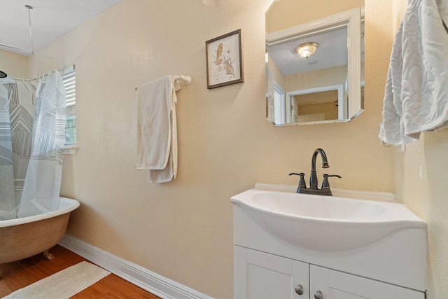 full bathroom featuring vanity, baseboards, and wood finished floors