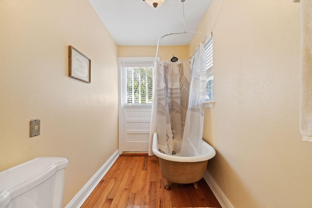 bathroom with toilet, baseboards, and wood finished floors