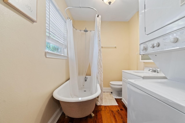 full bathroom featuring baseboards, wood finished floors, toilet, and stacked washer / drying machine