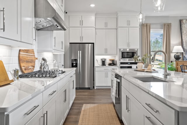 kitchen with under cabinet range hood, stainless steel appliances, a sink, white cabinets, and decorative light fixtures