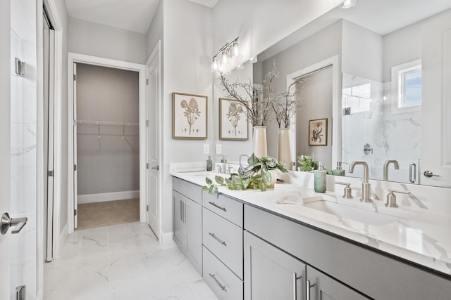 bathroom with a walk in closet, marble finish floor, double vanity, a stall shower, and a sink