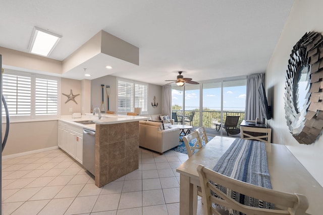 kitchen featuring dishwasher, light tile patterned floors, a sink, and a wealth of natural light