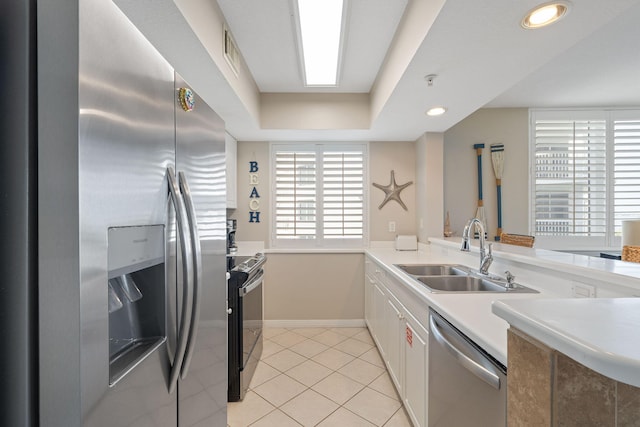 kitchen featuring light tile patterned floors, white cabinets, stainless steel appliances, light countertops, and a sink