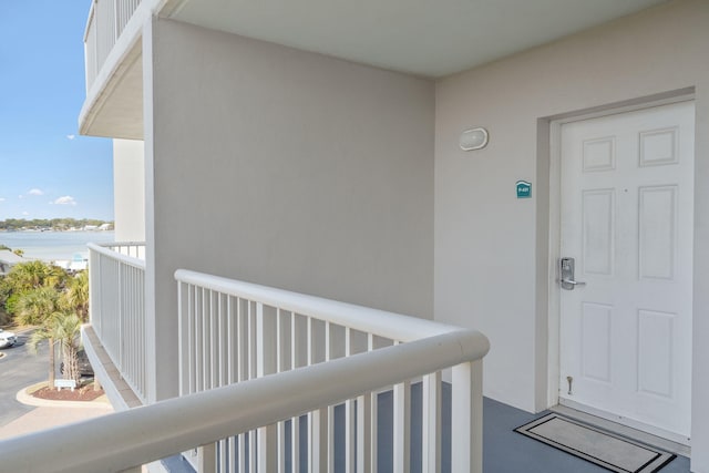 view of exterior entry featuring a balcony, a water view, and stucco siding