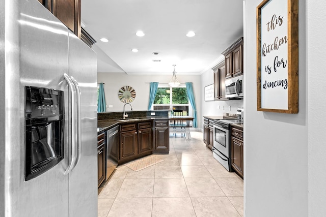 kitchen featuring light tile patterned floors, stainless steel appliances, a sink, dark brown cabinets, and decorative light fixtures