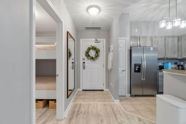 kitchen featuring light tile patterned flooring, stainless steel fridge, visible vents, and gray cabinetry