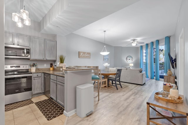 kitchen with gray cabinetry, ceiling fan with notable chandelier, a peninsula, open floor plan, and appliances with stainless steel finishes