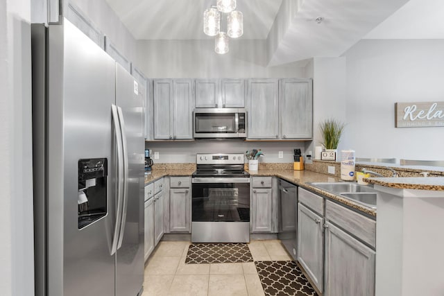 kitchen featuring light tile patterned floors, a peninsula, light stone countertops, stainless steel appliances, and a sink