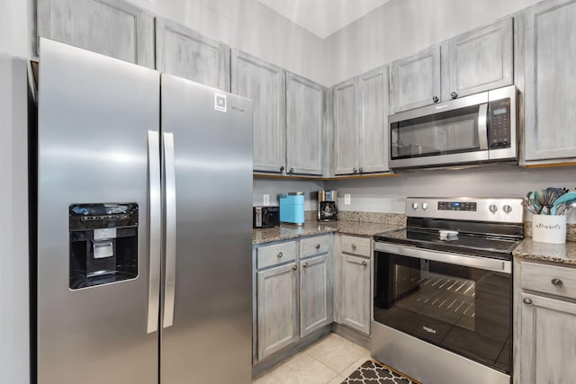 kitchen featuring stainless steel appliances, stone countertops, and light tile patterned floors