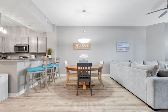 dining room featuring a ceiling fan, light wood-type flooring, visible vents, and baseboards