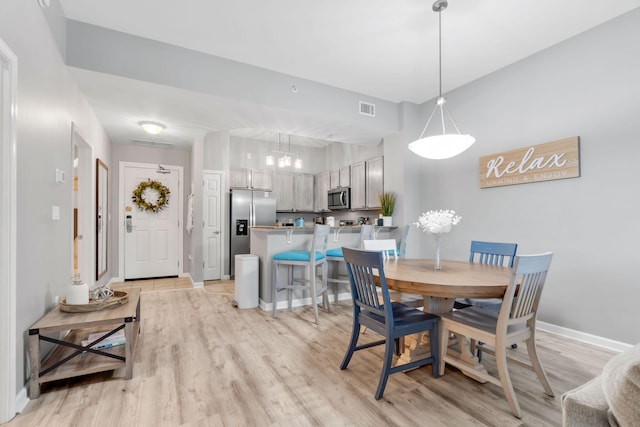 dining room with visible vents, light wood-style flooring, and baseboards