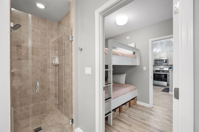 bathroom featuring a shower stall, baseboards, and wood finished floors