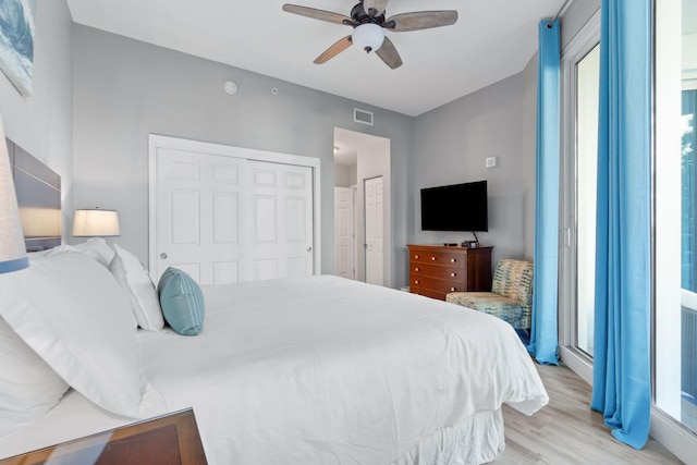 bedroom featuring light wood-style floors, ceiling fan, visible vents, and a closet