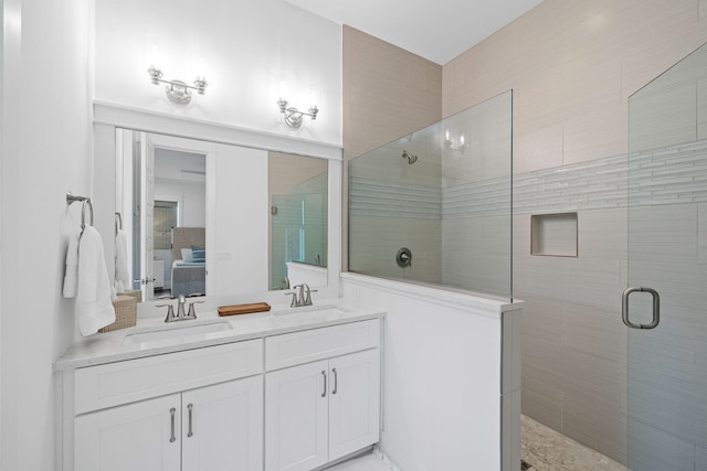 ensuite bathroom featuring double vanity, tiled shower, and a sink