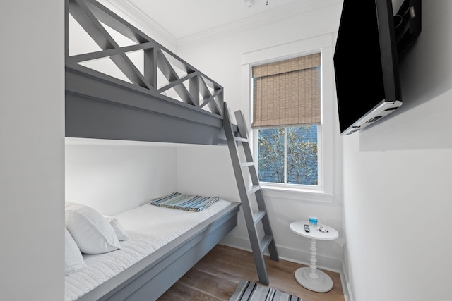 bedroom with ornamental molding, baseboards, and wood finished floors