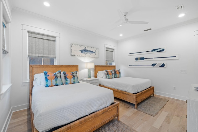 bedroom with light wood finished floors, ornamental molding, visible vents, and baseboards