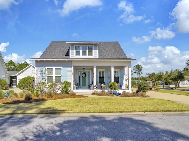 view of front of house featuring a front yard, covered porch, and roof with shingles