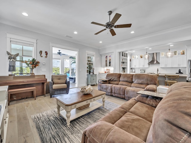 living room featuring light wood finished floors, recessed lighting, visible vents, and crown molding