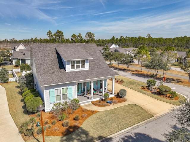 view of front of house featuring covered porch, fence, driveway, roof with shingles, and a front lawn