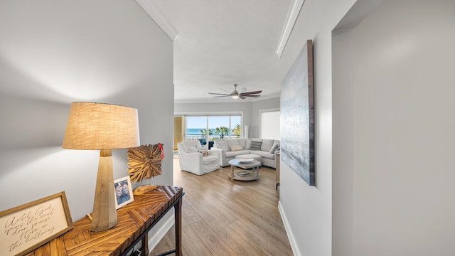 living area with ceiling fan, ornamental molding, light wood-style flooring, and baseboards