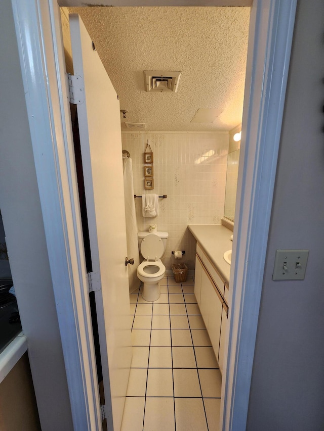 full bathroom with a shower with shower curtain, toilet, tile patterned floors, a textured ceiling, and vanity