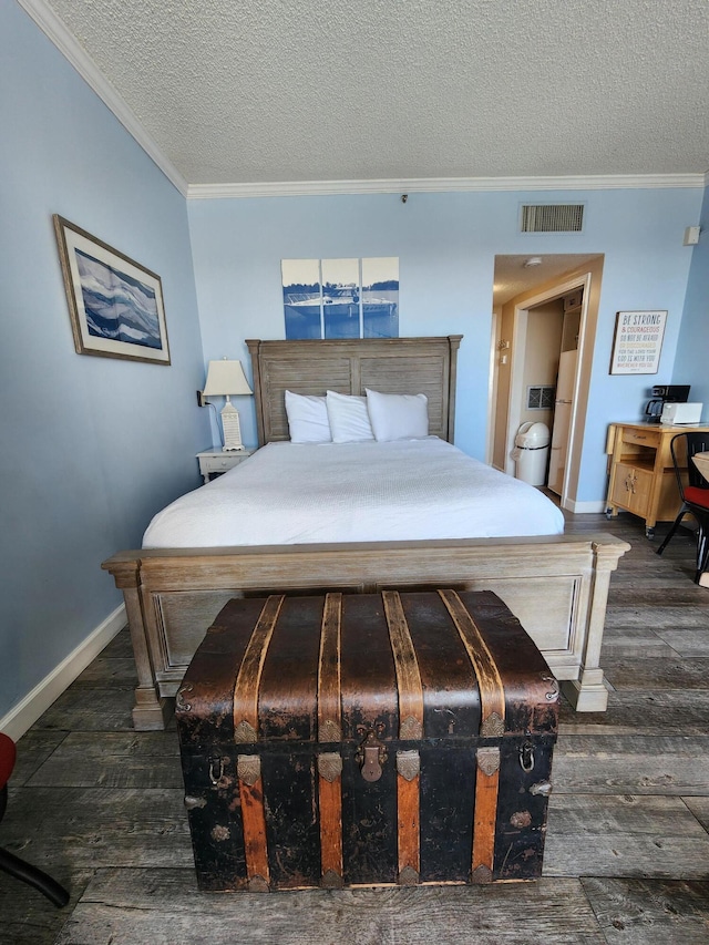 bedroom featuring baseboards, wood finished floors, visible vents, and crown molding