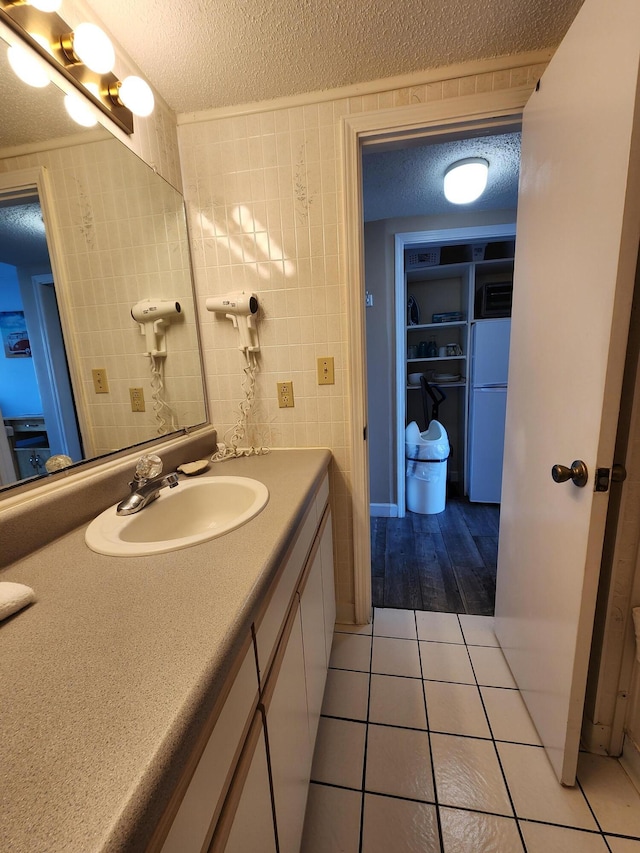 bathroom featuring a textured ceiling, vanity, tile patterned flooring, and tile walls