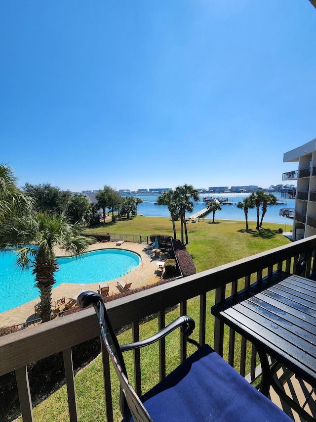 outdoor pool with a water view and a lawn