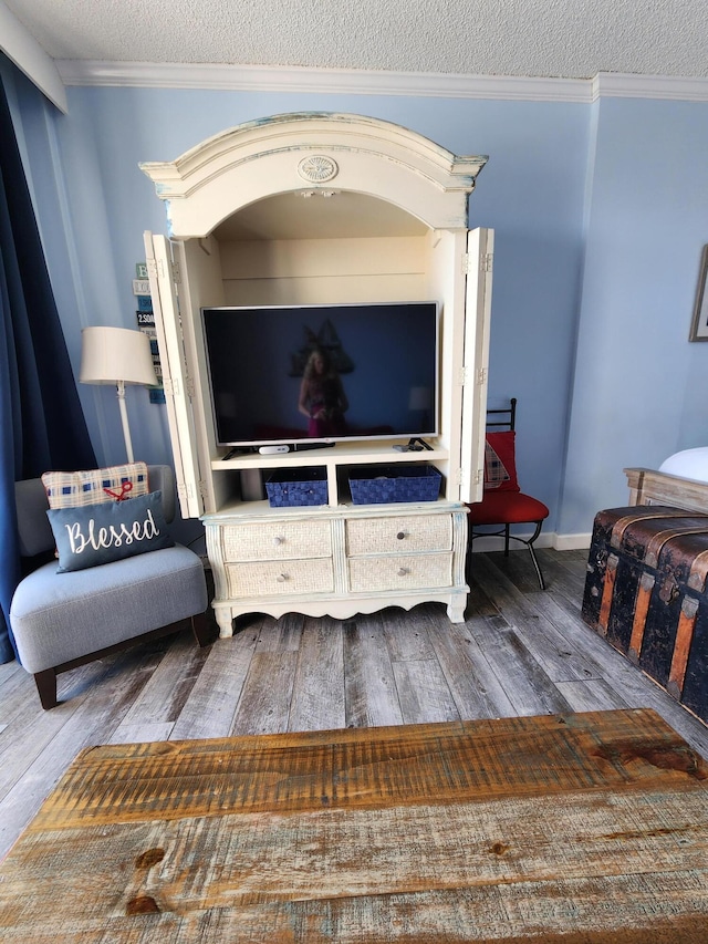 living area featuring crown molding, a textured ceiling, baseboards, and hardwood / wood-style flooring