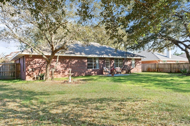 back of property with a yard, brick siding, and fence