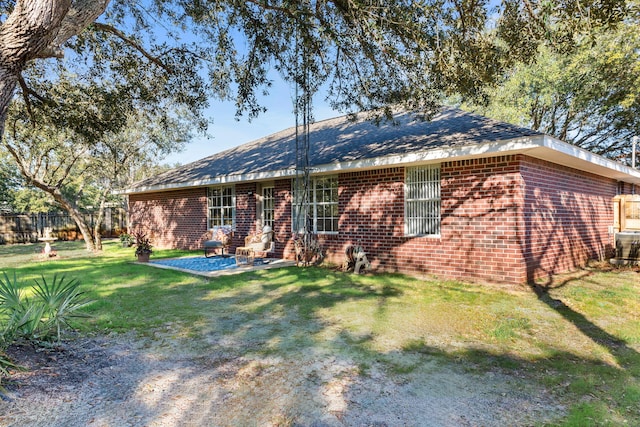 exterior space featuring a patio area, fence, a lawn, and brick siding