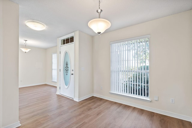 entrance foyer featuring a textured ceiling, baseboards, and wood finished floors