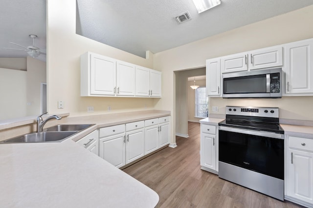 kitchen featuring a sink, visible vents, light countertops, appliances with stainless steel finishes, and light wood-type flooring