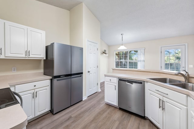 kitchen featuring a sink, light wood-style floors, vaulted ceiling, white cabinets, and appliances with stainless steel finishes