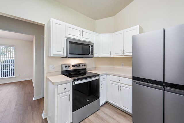 kitchen featuring appliances with stainless steel finishes, white cabinets, light countertops, and light wood finished floors