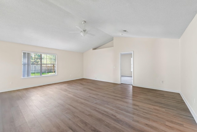 spare room with lofted ceiling, ceiling fan, a textured ceiling, wood finished floors, and baseboards