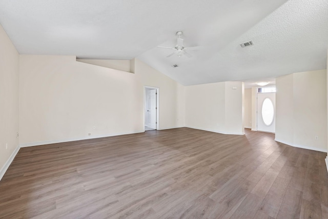 unfurnished living room featuring visible vents, vaulted ceiling, ceiling fan, a textured ceiling, and wood finished floors