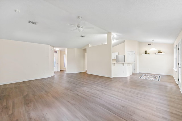 unfurnished living room with visible vents, vaulted ceiling, light wood finished floors, and ceiling fan