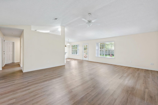 unfurnished living room with lofted ceiling, light wood finished floors, ceiling fan, and a textured ceiling