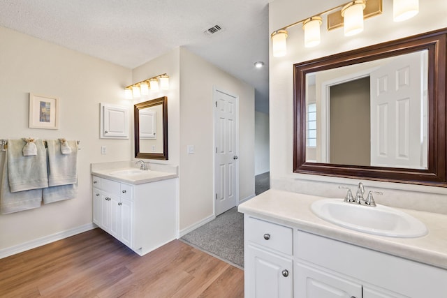 bathroom with two vanities, visible vents, a sink, and wood finished floors