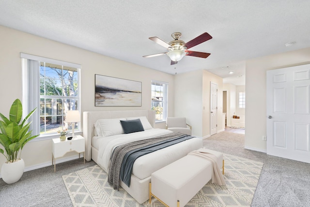 bedroom featuring light colored carpet, ensuite bath, a textured ceiling, and baseboards