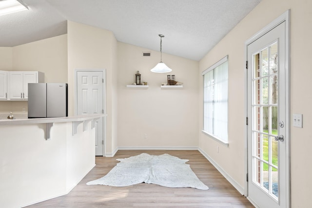 interior space with lofted ceiling, a textured ceiling, and plenty of natural light