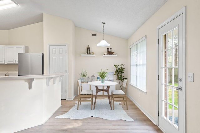 dining space featuring plenty of natural light, vaulted ceiling, and a textured ceiling