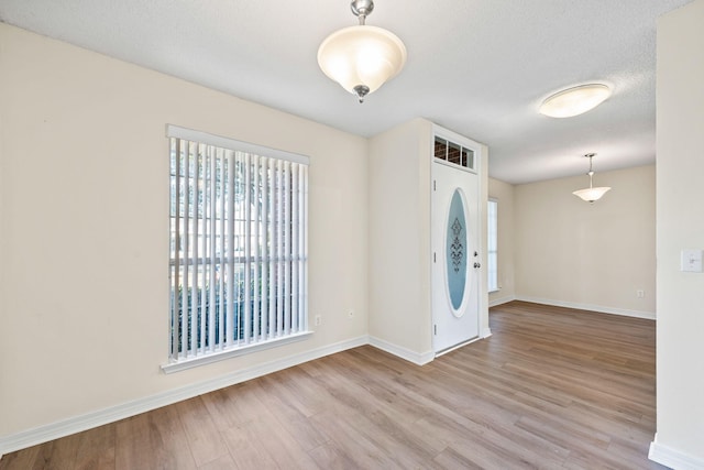 foyer entrance featuring a textured ceiling, wood finished floors, and baseboards