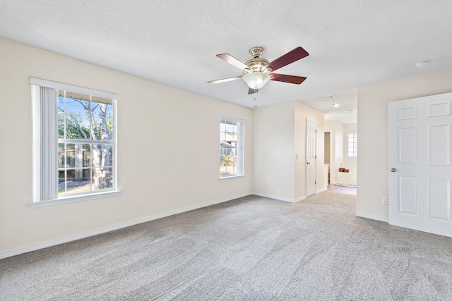 carpeted spare room featuring a ceiling fan, a textured ceiling, and baseboards