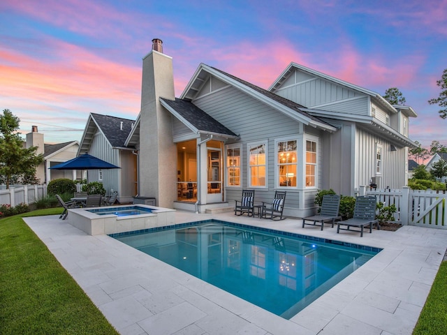 back of house featuring a patio, an in ground hot tub, fence, a fenced in pool, and a chimney